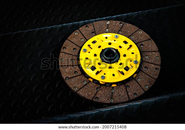 Yellow aluminum car clutch disc, on steel\
plate and black\
background.
