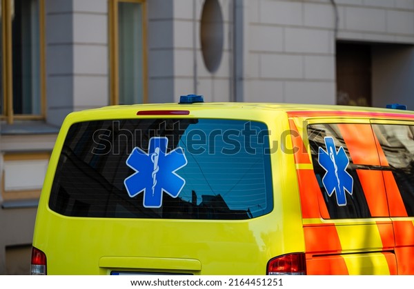 a yellow ambulance\
emergency car parked on the side of a crowded street, closeup,\
selective focus