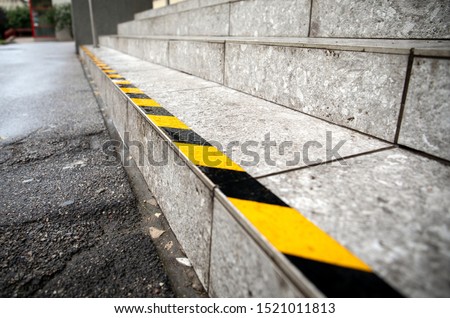 Yellow anti slip warning tape on stairs outdoors for safety. Public building