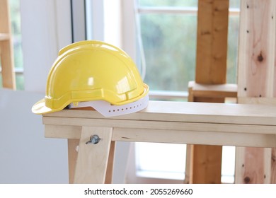 Yellow antiknock helmet on wooden table at carpentry woodwork workshop, personal protective equipment (PPE) at work place concept. - Powered by Shutterstock