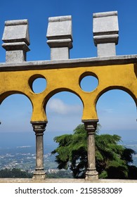 Yellow arched window in the terrace of Pena Palace or Palácio da Pena on the top of a hill in the blue sky background. National monument with sharp of architectural styles and colors
