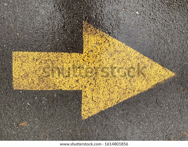 Yellow\
arrow painted on the asphalt. Direction\
concept.