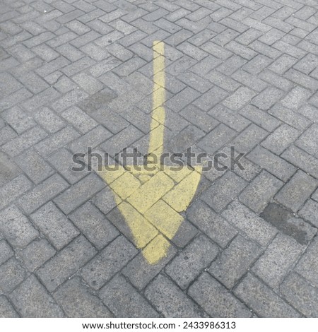 Yellow arrow pointing down or backwards on the old paving floor