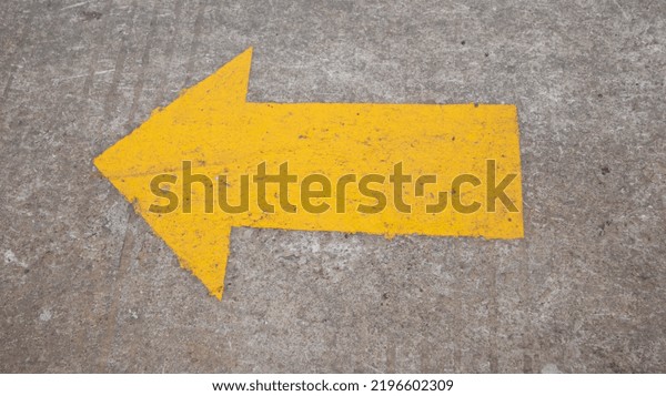 Yellow arrow symbol painted on\
asphalt on the road. Asphalt road yellow marking. Direction\
arrow