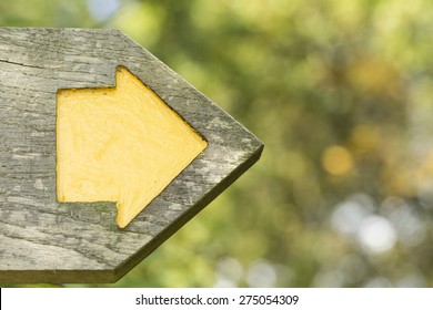 Yellow arrow within a wooden signpost pointing to a direction