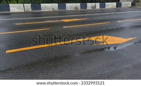 Yellow arrows of road markings in rainy weather.
