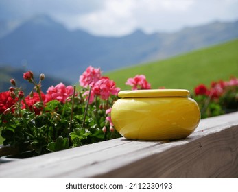 Yellow ashtray standing in front of fresh flowers and mountain scenery
