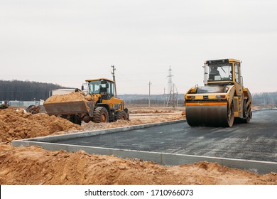 yellow asphalt compactor at work and orange bulldozer with sand - Powered by Shutterstock