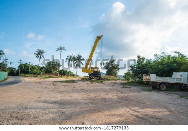 Yellow automobile crane with risen telescopic\
boom outdoors. Mobile construction crane on a constructin site.\
Crane machine stand by waiting for work under the construction\
building. Heavy\
industry.