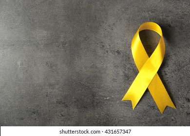 Yellow awareness ribbon on grey textured background