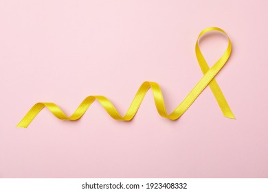 Yellow awareness ribbon on pink background, space for text