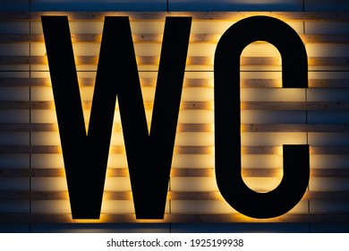 Yellow Backlit Black WC Sign On Wooden Strips Wall