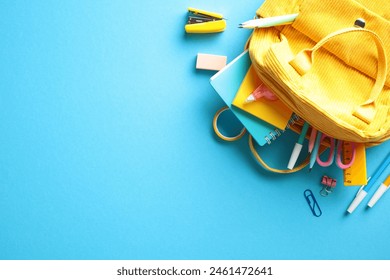 Yellow backpack with colorful school supplies, notebooks, pens, pencils, markers, scissors, eraser, and paper clips, all set against a striking blue background. Perfect for back-to-school campaigns - Powered by Shutterstock