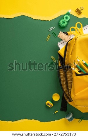 Yellow backpack packed with pencils, scissors, ruler and notebook on green and yellow paper background highlighting backtoschool and study preparation