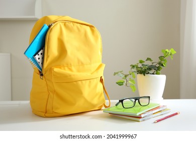 Yellow backpack and stack of notepads on table home. School supplies. Back to school concept. Educational design objects. Home studies.Schoolbag.