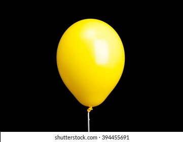 Yellow balloon on white ribbon isolated on black background