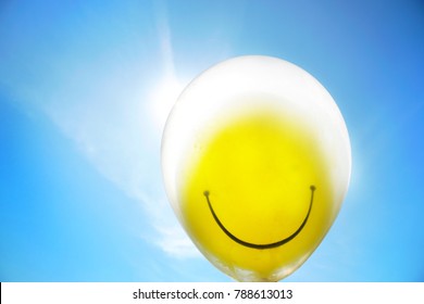 The yellow balloon smile face floating in the air  and blue sky. Free copy space. Happy holiday concept, silhouette light and toned image. - Powered by Shutterstock