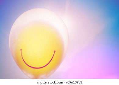 The yellow balloon smile face floating in the air  and blue sky. Free copy space. Happy holiday concept, ultra violet toned image. - Powered by Shutterstock