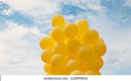 Yellow balloons floating on blue sky background