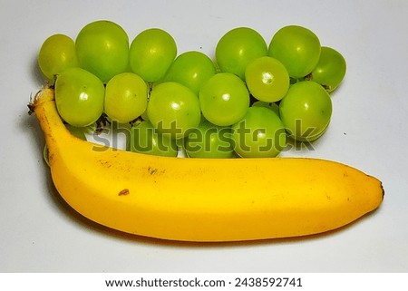 Yellow banana Cavendish and green grapes on a white background
