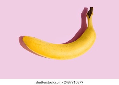 A yellow banana lies on a pink background, contrast, hard shadows. Minimalist composition - Powered by Shutterstock