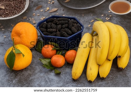 yellow banana and orange color clementines groupped. selective focus. closeup view. reflective surface. healthy eating. vitamin C, B and potassium. antioxides. tropical fruits. vegetarian lifestyle.