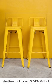 yellow bar stools with yellow panel background. yellow metal high chiars in front of restaurant wall. vertical picture.