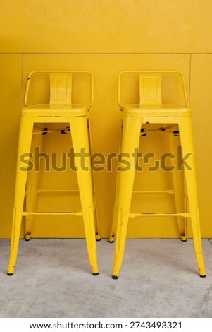 yellow bar stools with yellow panel background. yellow metal high chiars in front of restaurant wall. vertical picture.