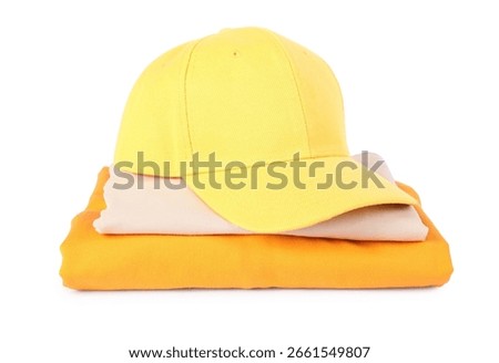 Yellow baseball cap and stack of folded t-shirts isolated on white. Mockup for design
