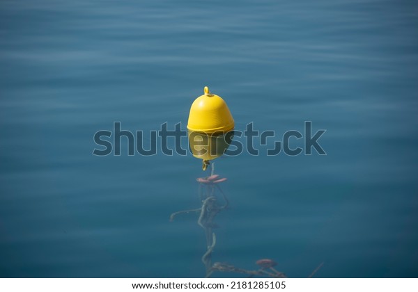 A yellow\
beacon buoy in the sea for beach marking and cross channel limits\
with blue sky and fish underwater, split view half over and under\
water surface, Mediterranean,\
Greece