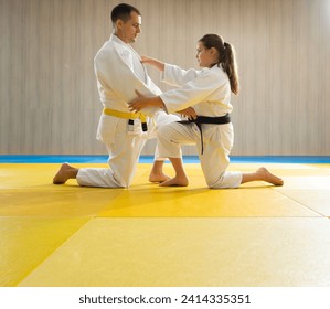 Judo de cinturón amarillo en judogi blanco y judo de cinturón negro joven en judogi blanco