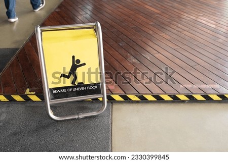 yellow beware of uneven floor sign board on tile floor. A warning sign of uneven level floor on the slippy floor. Close up slip warning sign on the ground.