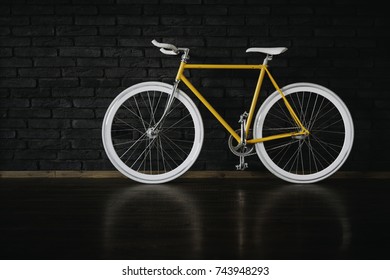Yellow bicycle on black brick wall.