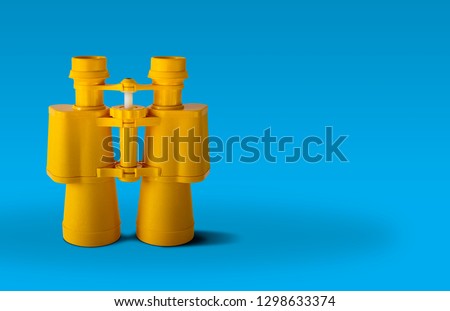 Yellow binoculars isolated on blue background