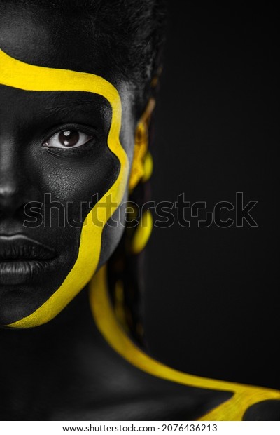 Yellow and black body paint. Woman with face art.\
Young girl with colorful bodypaint. An amazing afro american model\
with makeup.