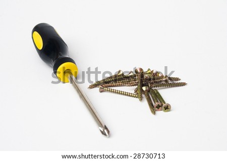 Yellow and black handled phillips screwdriver with pile of scews on white background