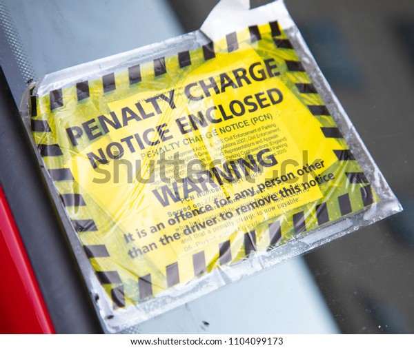 A yellow and black parking penaty\
charge notice attached to a parked car Liverpool May\
2018