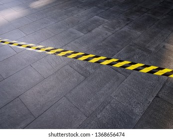 Yellow Black Safety Warning Tape On Tiled Floor Covering Electrical Cable Underneath