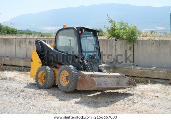 yellow and black small\
bulldozer outside 