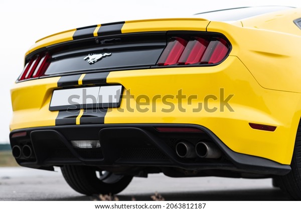 Yellow with\
black stripes Ford Mustang muscle car in a parking lot. Back, side\
view. Russia, Rostov-on-Don 23\
Oct2021