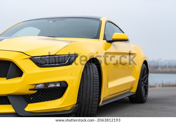 Yellow with black\
stripes Ford Mustang muscle car in a parking lot. Russia,\
Rostov-on-Don 23 Oct2021