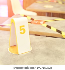 Yellow black tape in cafe. Social distance. Separate people in restaurant. Order number at table. Waiting food in fastfood cafeteria. Mcdonald interior