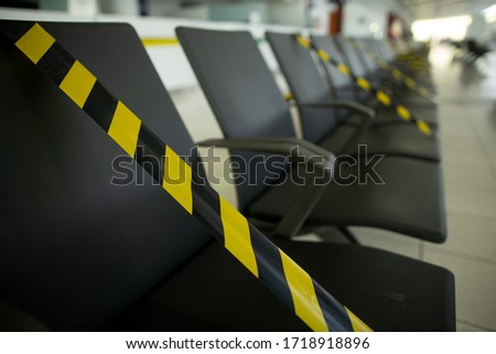 Yellow and black warning sign taping marked on public chairs 1.5 m apart as social distancing Coronavirus - 19 protection       