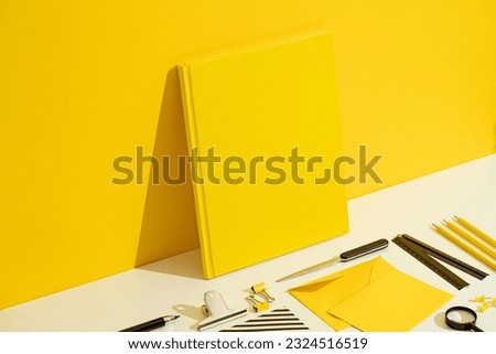 Yellow blank hardcover book and stationary mockup, template on yellow and white background. Stationary flat lay, back to school