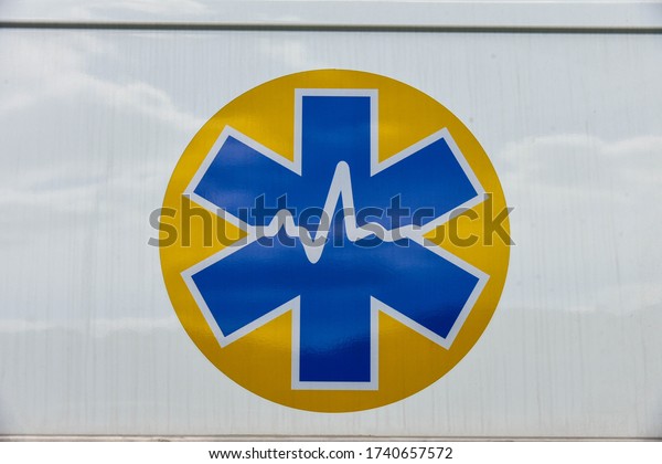 Yellow and\
blue emergency medical sign on a white\
car
