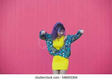 yellow, blue and pink photo of a teen woman with afro hair listening and dancing to the music