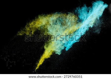 Yellow and blue powder exploding against black background