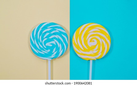 Yellow and blue swirl lollipops isolated on blue and yellow background. Top view flat lay. Colorful lollipop background.