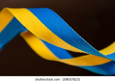 Yellow and blue, Ukrainian national flag colors, fabric ribbon on dark mirror glass with reflection background. Ukraine nation independence celebration symbol