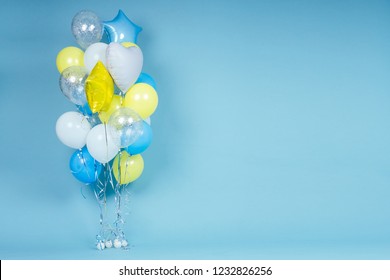 yellow, blue and white balloons on blue wall background copy space. Colorful balloon in room prepared for birthday party. copyspace helium balloons